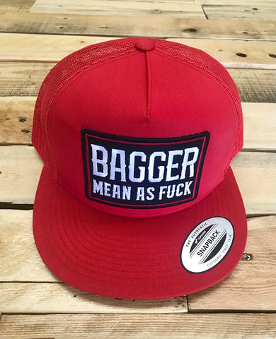 Red cap with a patch reading 'Bagger Mean as Fuck' on a wooden surface
