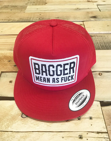 Red cap with 'Bagger Mean as Fuck' text on a wooden surface