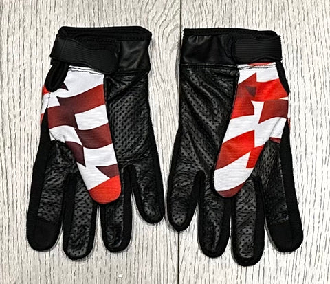 Pair of gloves with black, red, and white design on a wooden surface