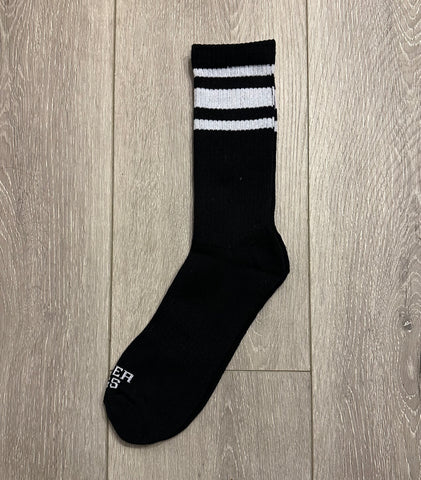Black sock with white stripes on a wooden floor