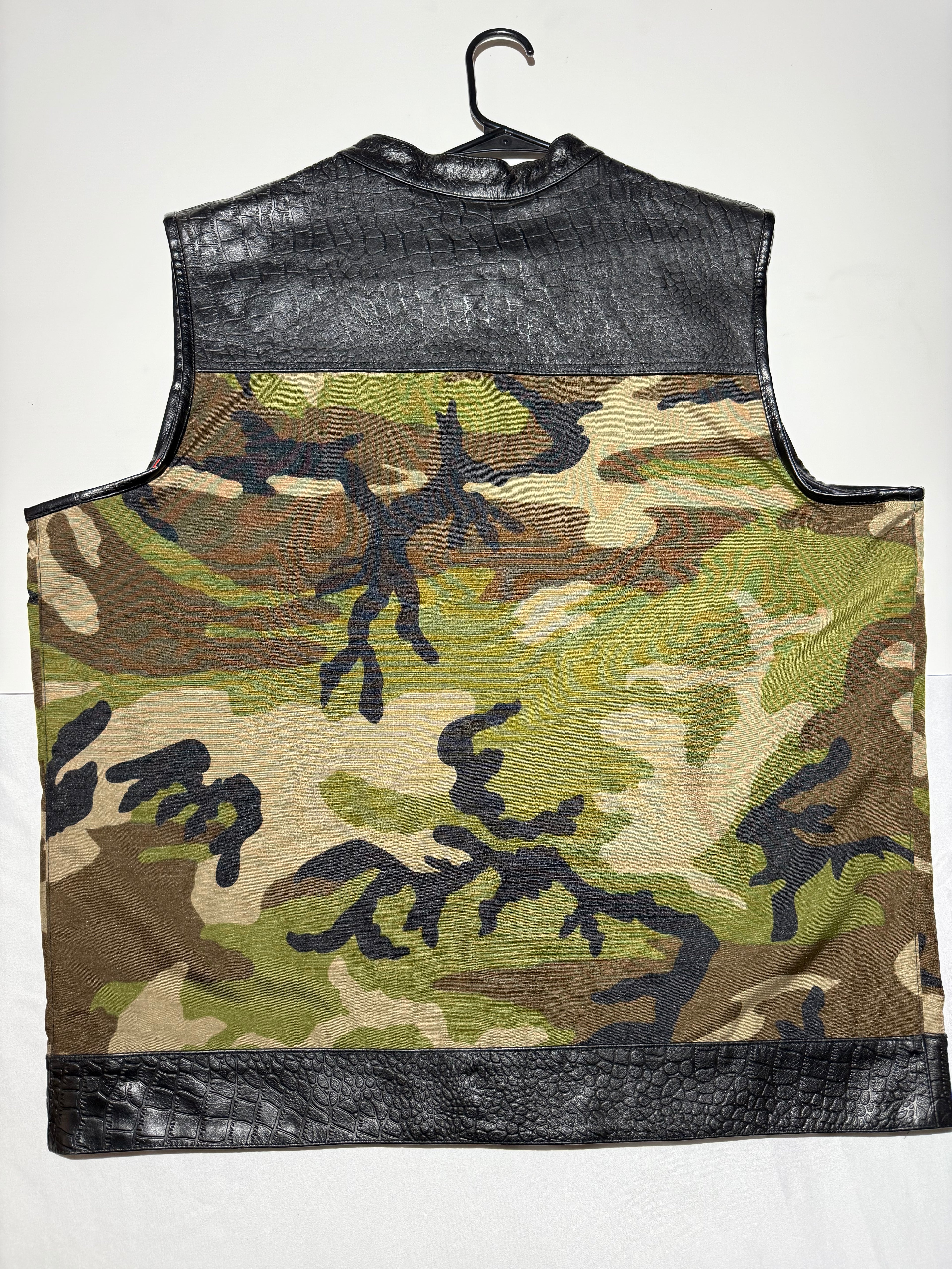 Camouflage-patterned vest with black leather accents on a white background