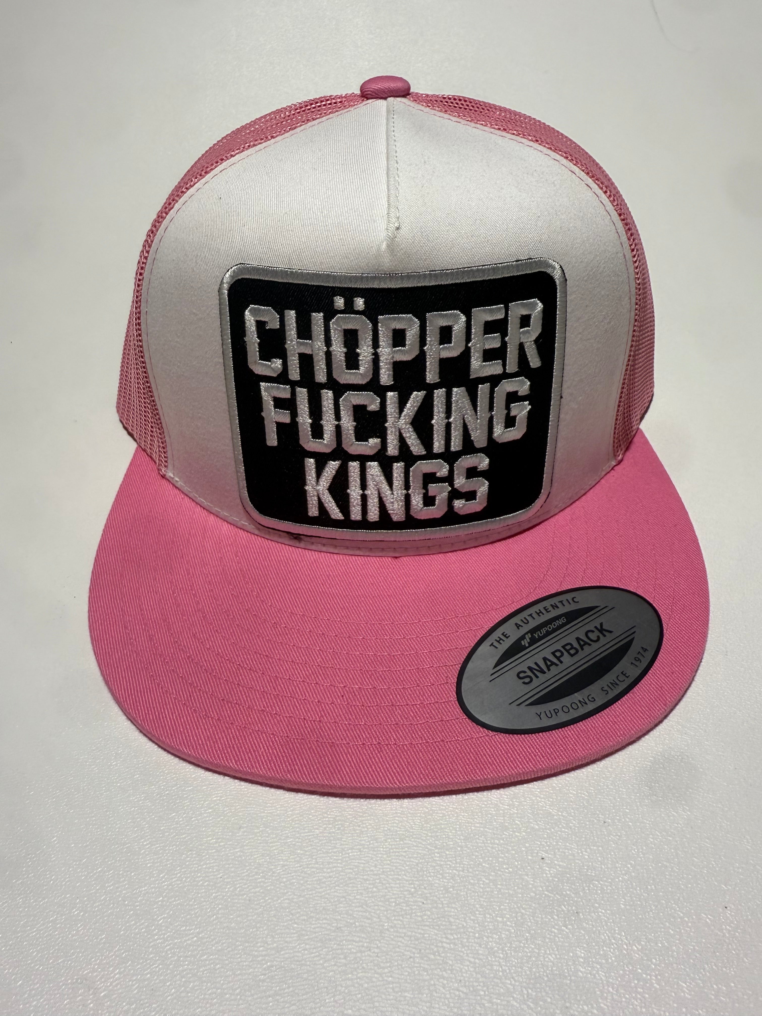 Pink and white cap with a black patch displaying text on a light gray background