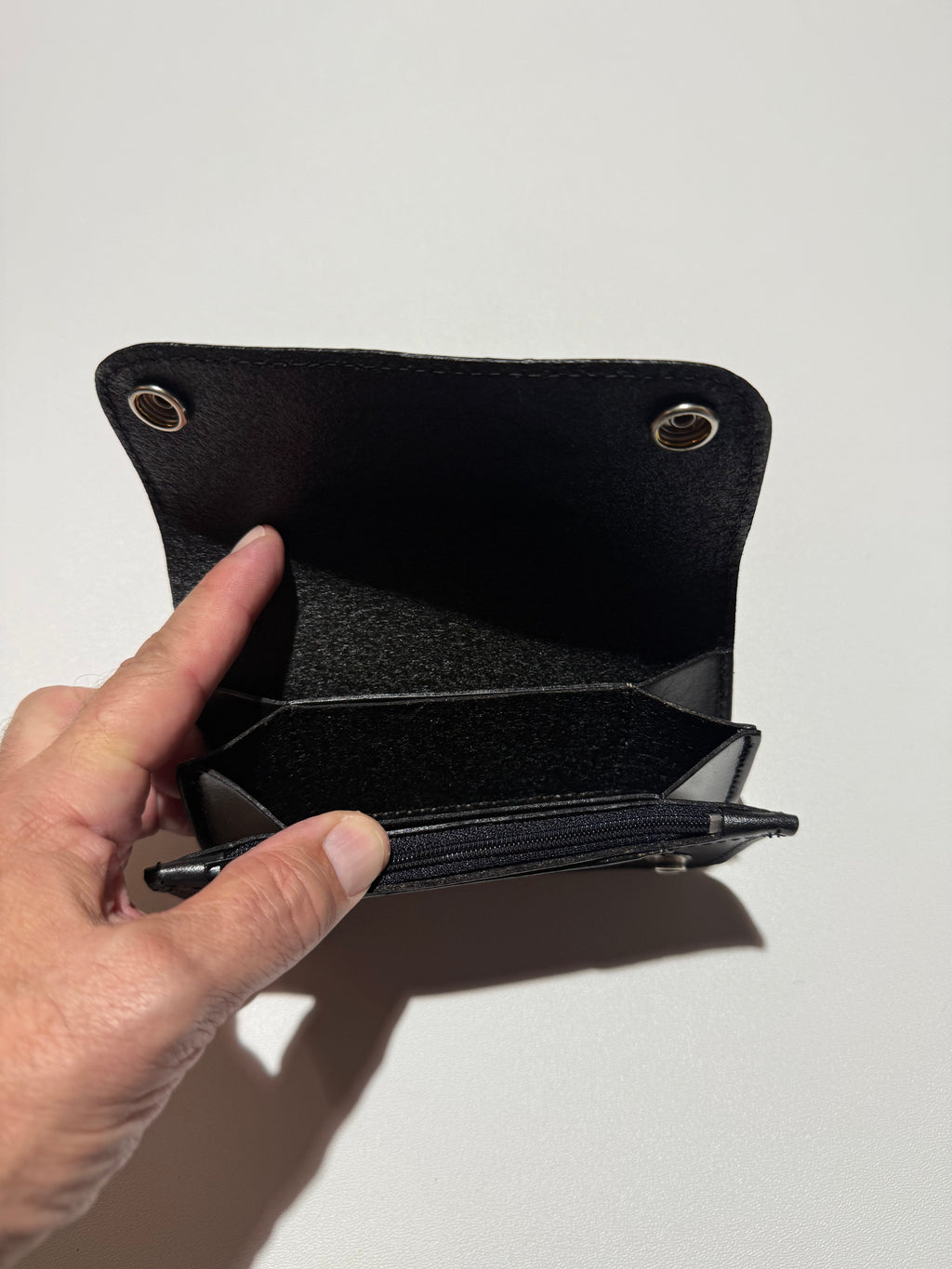 Hand holding a black wallet against a white background