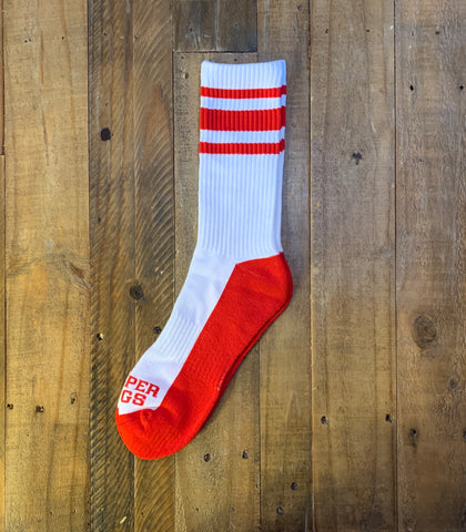 White and red sock with 'PER GS' branding on a wooden background