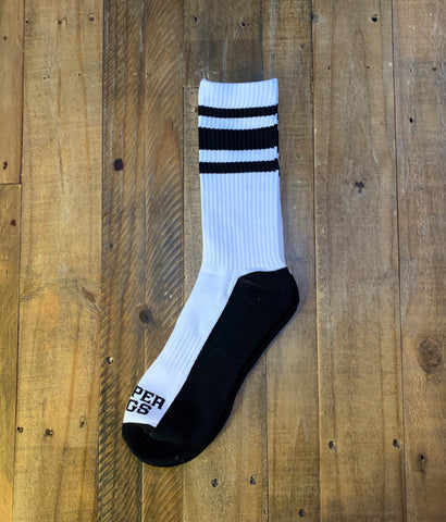 White and black sock with three stripes on a wooden surface